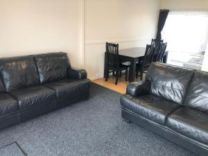 a living room with a leather couch and a table at Twin Coast Adventures Motel & Cycle Hire in Kaikohe