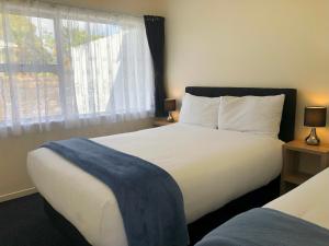 a bedroom with a large white bed and a window at Twin Coast Adventures Motel & Cycle Hire in Kaikohe +28 photos
