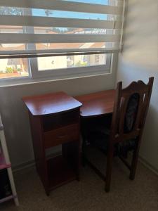 a wooden desk and chair in a room with a window at Pieza privada en casa in San Pedro de la Paz