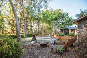 a group of people sitting around a fire pit in a yard at Wilderness House in Kulangoor