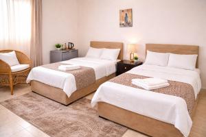 a bedroom with two beds and a chair in it at Hur palace pyramids view in Cairo