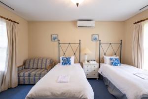 a bedroom with two beds and a chair at フォレストヒルズガーデン in Mihara