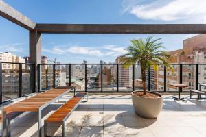 a balcony with benches and a palm tree on a building at Apartamento ensolarado em condomínio clube in Curitiba