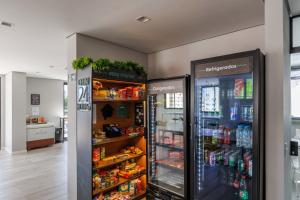 two refrigerators in a store with food and drinks at Apartamento ensolarado em condomínio clube in Curitiba