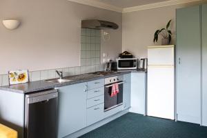 a kitchen with white cabinets and a white refrigerator at Aston Norwood Chalets in Upper Hutt