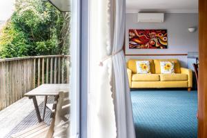 a living room with a yellow couch on a balcony at Aston Norwood Chalets in Upper Hutt +10 photos