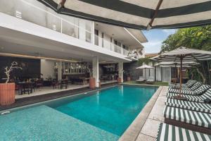 an image of a swimming pool with chairs and umbrellas at Monolocale Resort & Spa Seminyak by Ini Vie Hospitality in Seminyak