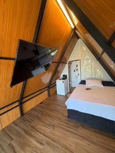 a room with a bed and a flat screen tv at Chalé refugio de Igaratá in Igaratá