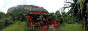 a small red building with a mountain in the background at Casa Morro Branco in Palmeiras