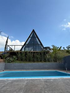 a glass house with a swimming pool in front of it at Chalé refugio de Igaratá in Igaratá