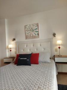 a bedroom with a large white bed with two lamps at Mirasol in Villa Carlos Paz +18 photos