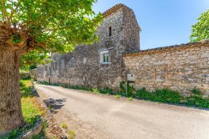 a stone building with a tree next to a road at L'atelier de Raymond in Verfeuil +15 photos