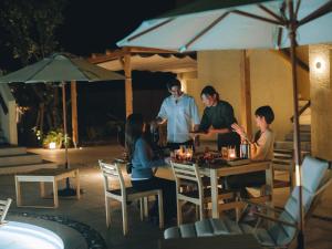 a group of people sitting at a table with an umbrella at semilla 名護 沖縄 in Nago