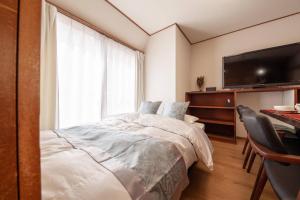 a bedroom with a bed and a desk and a television at Daini Kuwamura Building 4th in Tokyo