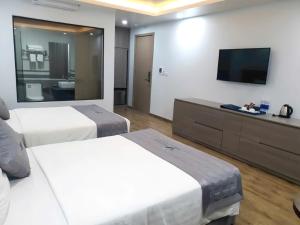 a hotel room with two beds and a flat screen tv at Bamboo Hotel FLC Sầm Sơn in Sầm Sơn