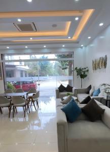 a living room with a couch and a table with chairs at Bamboo Hotel FLC Sầm Sơn in Sầm Sơn