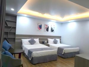 a hotel room with two beds and a chair at Bamboo Hotel FLC Sầm Sơn in Sầm Sơn