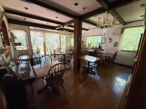 a dining room with tables and chairs and windows at ray of hakuba 白馬の輝き in Hakuba