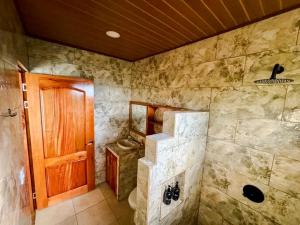 a bathroom with a toilet and a wooden door at Rio Celeste Birds Garden Apartments with air conditioning and Wifi Starlink in Upala +68 photos
