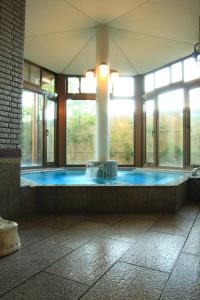 a large room with a hot tub with windows at Yabukiso in Yamanakako