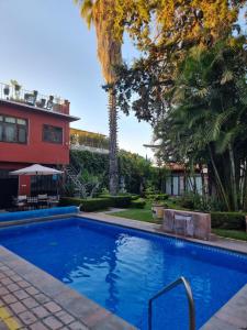 a swimming pool in front of a house with palm trees at Hacienda de las Flores in San Miguel de Allende
