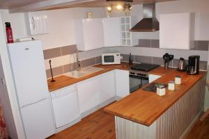 a kitchen with white cabinets and a wooden counter top at River Cottage - La Mare Chappey in Néhou