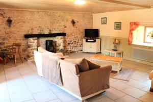 a living room with a couch and a fireplace at River Cottage - La Mare Chappey in Néhou