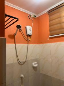 a shower in a bathroom with an orange wall at Cardo Homestay Siargao in General Luna