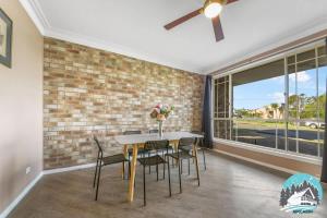 a dining room with a table and chairs and a brick wall at 3B house Central Coast parking in Blue Haven