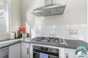 a white kitchen with a stove top oven at 3B house Central Coast parking in Blue Haven