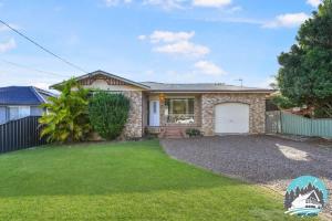 a house with a garage and a grass yard at 3B house Central Coast parking in Blue Haven