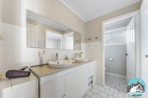 a white bathroom with two sinks and a mirror at 3B house Central Coast parking in Blue Haven +3 photos