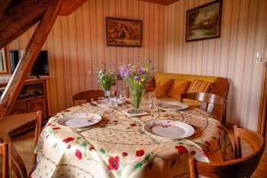 a dining room table with plates and flowers on it at Gîte le marlet in Saint-Alban-sur-Limagnole +13 photos
