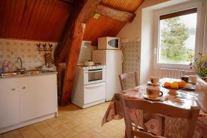 a kitchen with a table and a white refrigerator at Gîte le marlet in Saint-Alban-sur-Limagnole
