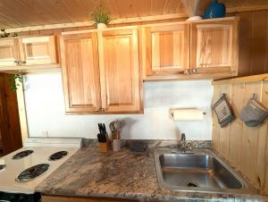 a kitchen with a sink and a stove and wooden cabinets at 2BR 1BA Cabin #2 Riverside Point Resort in Park Rapids +44 photos