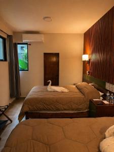 a hotel room with two beds with a swan on it at El Suburbio - Aldama in Morelia