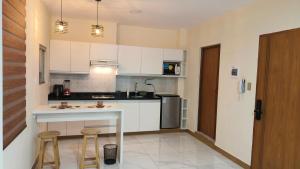 a kitchen with white cabinets and a table and stools at Hospedaje Smart Wasi Sucre in Sucre