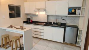 a kitchen with white cabinets and a table and stools at Hospedaje Smart Wasi Sucre in Sucre +6 photos