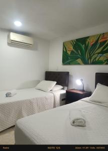 a room with two beds and a painting on the wall at Hotel Fegali Art Boutique in Cartagena de Indias