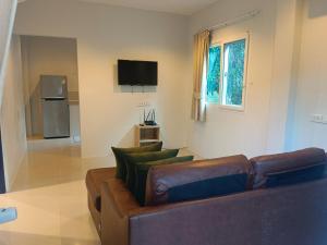 a living room with a brown couch and a television at Elevated Bungalow House 5 min from the beach 3-6 in Nathon Bay