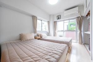 a bedroom with two beds and two windows at GoodStay505 in Kurume