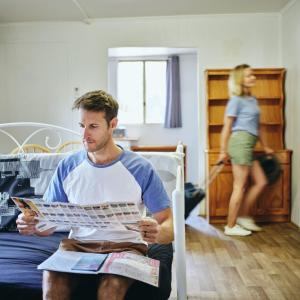 a man sitting on a bed reading a magazine with a woman at Collie Tourist Park in Collie
