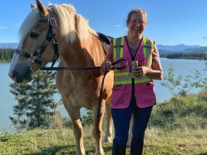 a woman is standing next to a horse at The Big Red Barn in Whitehorse