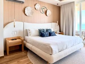 a bedroom with a large white bed with blue pillows at Hear the Waves Luxury Oceanfront Escape in Bucerías