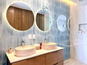 two sinks in a bathroom with two mirrors at Hear the Waves Luxury Oceanfront Escape in Bucerías
