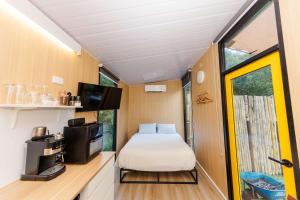 a bedroom in a tiny house with a bed and a tv at Cedar Creek Falls by Tiny Away in Mount Tamborine