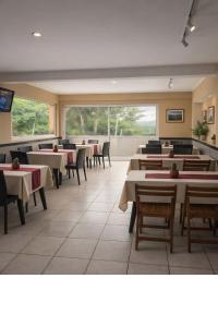 a dining room with tables and chairs and windows at Apart Hotel Belgrano in Perico