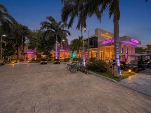 a parking lot in front of a building with palm trees at Hotel NEON by Playa Palmera Beach Resort in Punta Cana