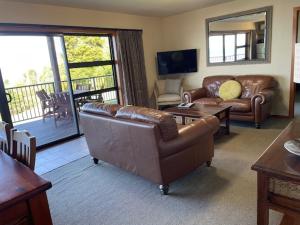 a living room with a leather couch and a table at Pukawa Villas Formerly Oreti Village Resort in Kuratau
