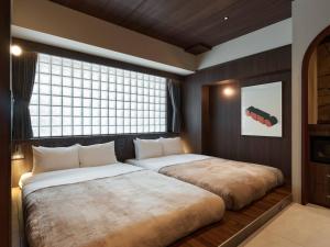 a bedroom with two beds and a window at illi Atra Aoyama in Tokyo
